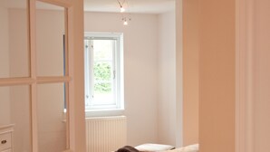 A bedroom with a bed, a window, and a radiator. - Das Backhaus 2 (Stoltebuell)