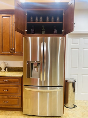 A stainless steel refrigerator with a freezer drawer, a water dispenser, and a built-in ice maker.
