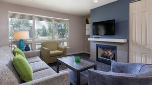 Een moderne woonkamer met een open haard, een televisie en comfortabele zitplaatsen.