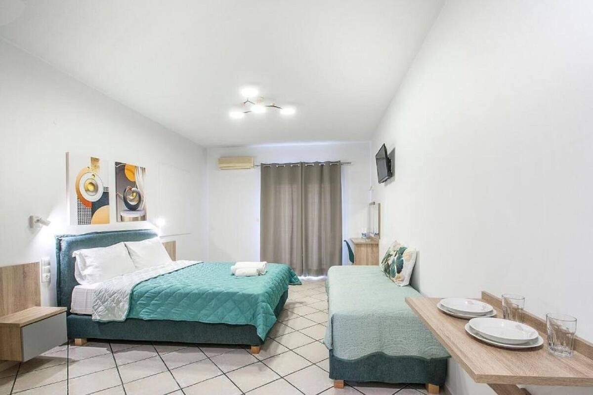 Habitación de hotel moderna con dos camas, una mesita con platos y vasos, televisor y obras de arte en las paredes.