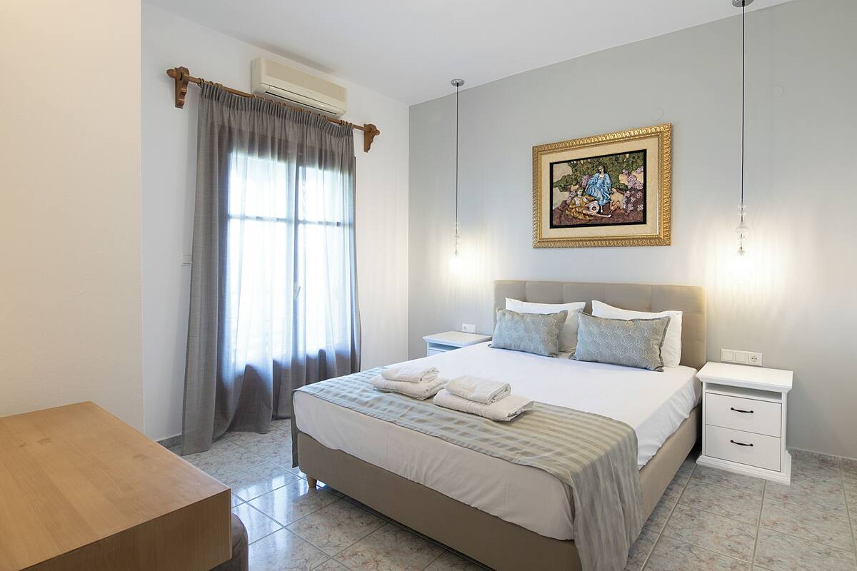 Un dormitorio ordenado con una cama grande, mesitas de noche y un cuadro en la pared.