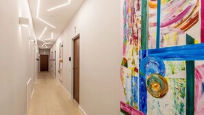A hallway with a modern design, featuring geometric ceiling lights and a colorful abstract painting on the wall. - Sweett | Duomo 2A - Two Bedroom Apartment, Sleeps 4 (Milano)