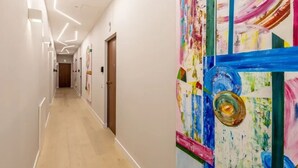 Un couloir doté d’un plancher en bois, de murs blancs et d’une peinture abstraite aux couleurs vives sur le mur de droite.