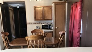 A kitchen with wooden cabinets, a microwave, and a dining table with four chairs.