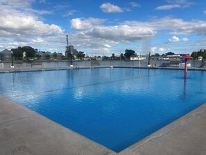 A rectangular swimming pool with clear blue water, surrounded by a concrete deck.