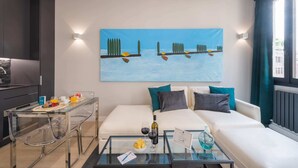 A modern hotel room with a glass dining table, a sofa set, and a painting on the wall. - Sweett | Duomo V - One Bedroom Apartment, Sleeps 3 (Milano)