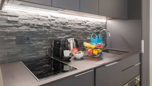 A modern kitchen with a built-in stove, a coffee maker, a fruit bowl, and a hanging bag. - Sweett | Duomo V - One Bedroom Apartment, Sleeps 3 (Milano)
