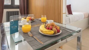 A breakfast setup with a glass table, a plate of fruit, a glass of orange juice, and a menu sign.