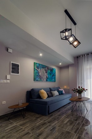 Ein modernes Wohnzimmer mit einem blauen Sofa, einem Holztisch und einem Gemälde an der Wand.