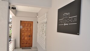 A hallway with a wooden door, a white security gate, and a sign reading "FENSICH HOUSE". - Athens Chic House Apt A3 40sq.m (Athina)