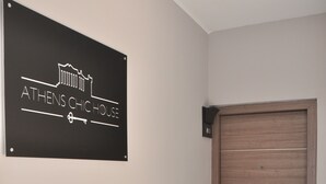 A sign reading "ATHENS CHIC HOUSE" on a wall, a wooden door, and a set of stairs leading to the door. - Athens Chic House Apt A3 40sq.m (Athina)