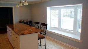 A kitchen with a large island, a window with blinds, and a dining area with chairs. - Stunning Home In A Leafy And Quiet Neighborhood (Jackson)