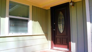 A front door with a glass panel, a small porch with a brick step, and a window with blinds. - Stunning Home In A Leafy And Quiet Neighborhood (Jackson)