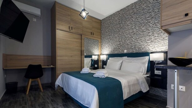 Moderni hotellihuone, jossa on sänky, työpöytä ja kiviseinä.
