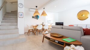 Una sala moderna con una escalera, un comedor y un reloj de pared grande.