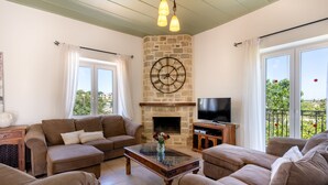 Una sala de estar con chimenea de piedra, un reloj grande y un televisor.