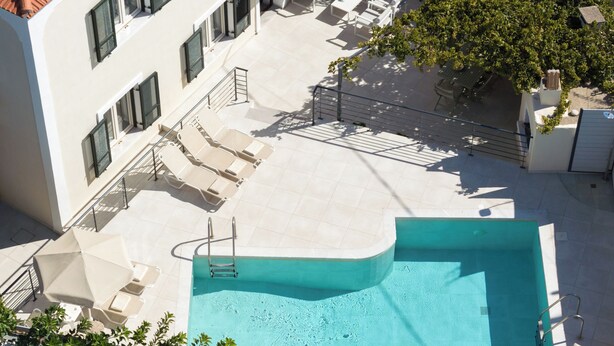 Un área de piscina en la azotea con sillones de descanso y una piscina.
