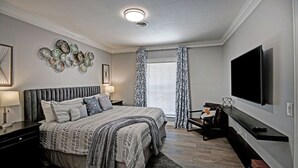 Un dormitorio moderno con una cama grande, un televisor de pantalla plana y un adorno en la pared.