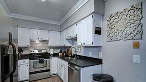 Una cocina moderna con armarios blancos, electrodomésticos de acero inoxidable y un elemento decorativo en la pared.