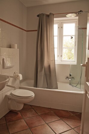A bathroom with a toilet, sink, and bathtub. - Das Backhaus 3 (Stoltebuell)