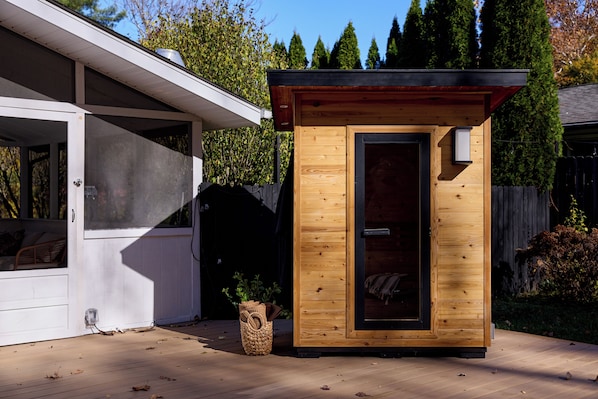 Una cabaña de madera con puerta, ventana y un pequeño porche.