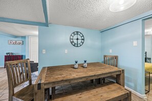 A dining area with a wooden table, chairs, a wall clock, and a 'Relax' sign.