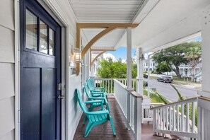 A porch with a black door, white railings, and green Adirondack chairs. - M Avenue Trio | Whole Historic Triplex • Sleeps 19 • Walk to Galveston Beach (Galveston)