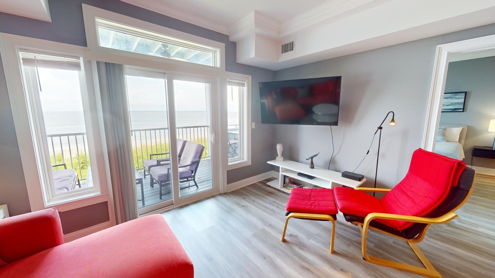 A modern hotel room with a balcony, a TV, and a desk.