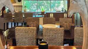 A restaurant with wicker furniture, a central dining table, and a view of the outdoors. - Private Boutique Villa in Rome – Pool, Jacuzzi & Garden, 20min to City (Rome)