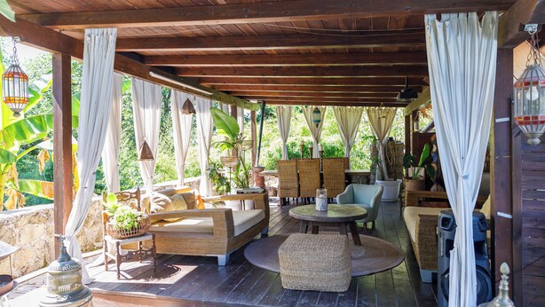 An outdoor covered patio with wicker furniture, a round table, and hanging lanterns. - Private Boutique Villa in Rome – Pool, Jacuzzi & Garden, 20min to City (Rome)