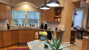 A modern kitchen with wooden cabinets, a granite island, and bar stools. - Plan for summer fun and fall color viewing.  Plenty of room for the family. (Hancock)