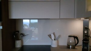 A kitchen with a view of the sea, a coffee maker, and a kettle on the counter. - Neptune 5, top floor (Menton)