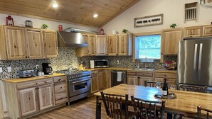 Une cuisine avec des meubles de rangement en bois, une cuisinière, un four à micro-ondes et un réfrigérateur.