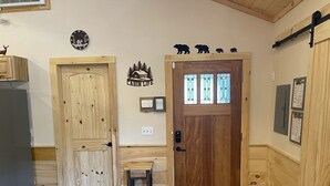 L’intérieur d’une cabane en bois, avec une porte en bois, un petit tabouret en bois et un paillasson.