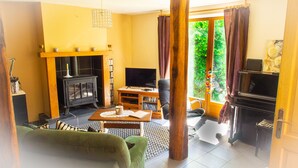 Un salon chaleureux avec une cheminée, un téléviseur et un canapé confortable.