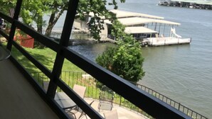 Uitzicht vanaf een balkon op een wateroppervlakte met boten, een steiger en begroeiing.