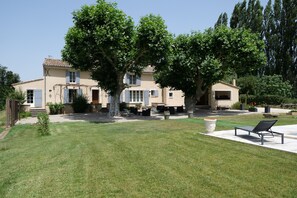 A two-story house with a large lawn, outdoor seating area, and a patio with a lounge chair. - Vacation rental house with pool CAVAILLON LS2-376 (Cavaillon)