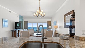 A modern kitchen with granite countertops, a built-in sink, and a chandelier. - Beachfront Escape! Perfect Beach! Relax by the Pool! Beach Manor 808 is Waiting! (Miramar Beach)