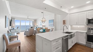 Een moderne keuken met witte kasten, een centraal eiland en een eetgedeelte met uitzicht op de oceaan.