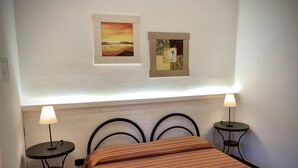 A hotel room with a bed, two bedside tables, and two wall-mounted lamps. - 35 sqm apartment with seafront veranda (2) (Sciacca)
