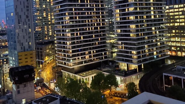 A modern high-rise building with multiple floors, large windows, and a well-lit facade. - Captivating 2-bed Apartment in Canary Wharf London (London)