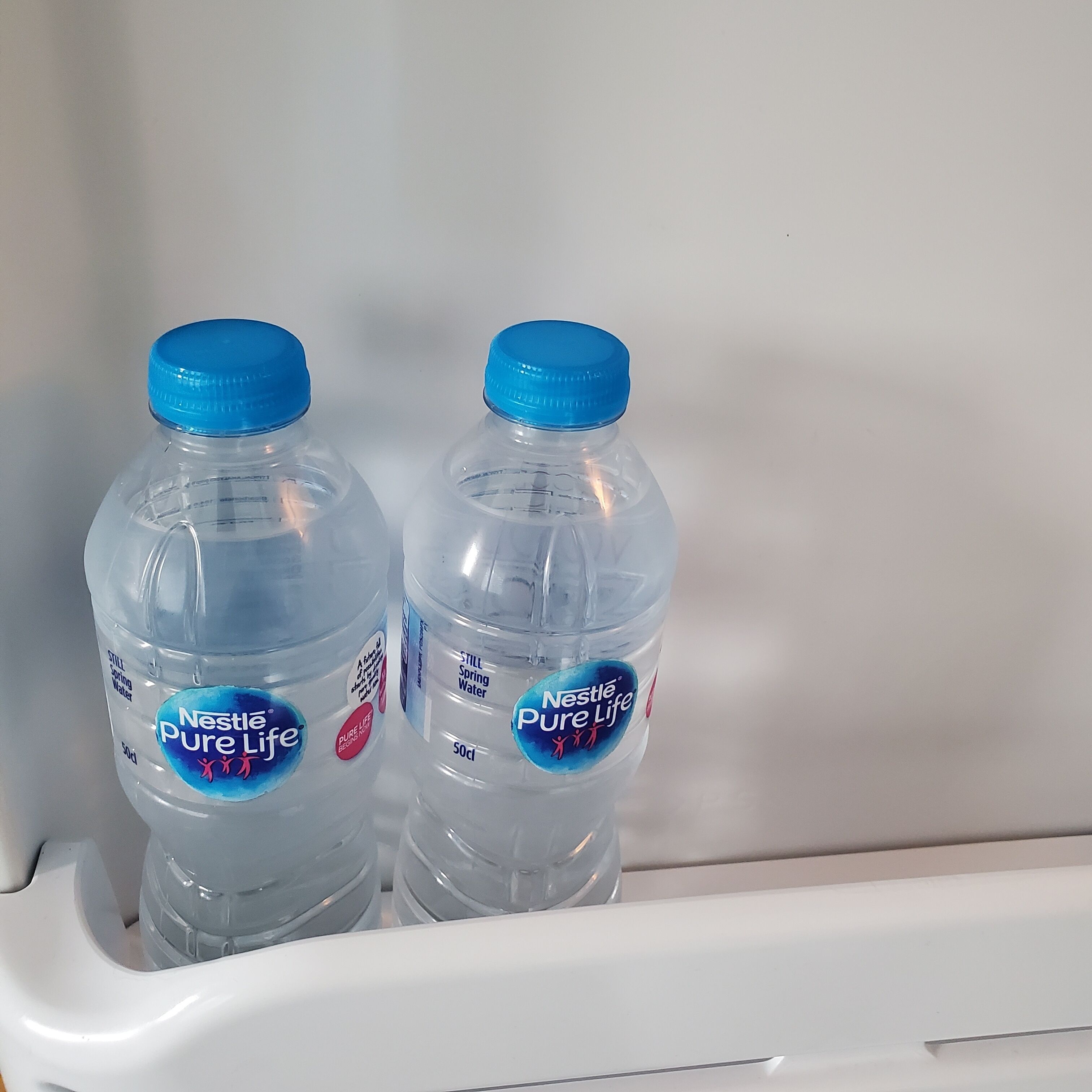 Two Nestlé Pure Life water bottles in a white refrigerator.