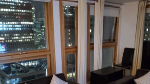 A modern living room with two leather sofas, a glass coffee table, and a view of a cityscape through large windows. - Captivating 2-bed Apartment in Canary Wharf London (London)