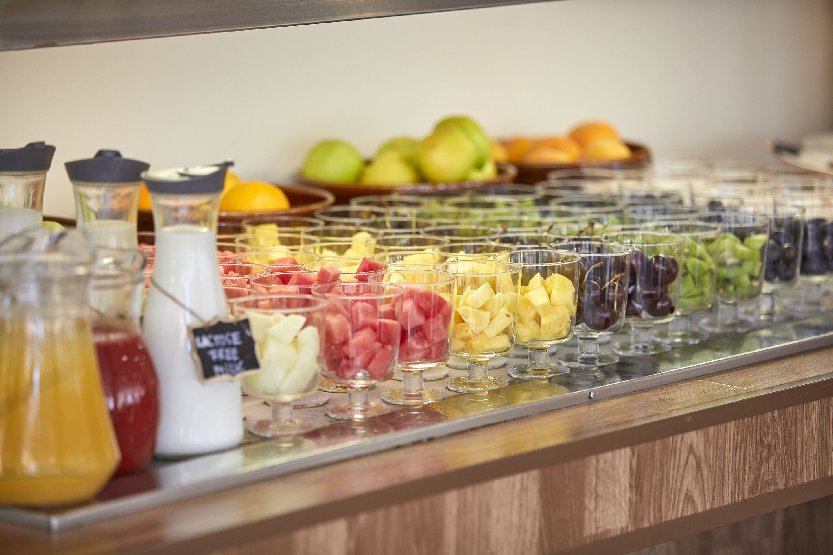 Un bufé con diversas frutas y una jarra de limonada.