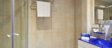 Une salle de bain avec une douche à parois de verre, un lavabo doté d’un plan de travail bleu et un miroir au-dessus du lavabo.
