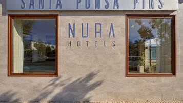 The exterior of NURA Hotels with a clear view of the signage and windows.