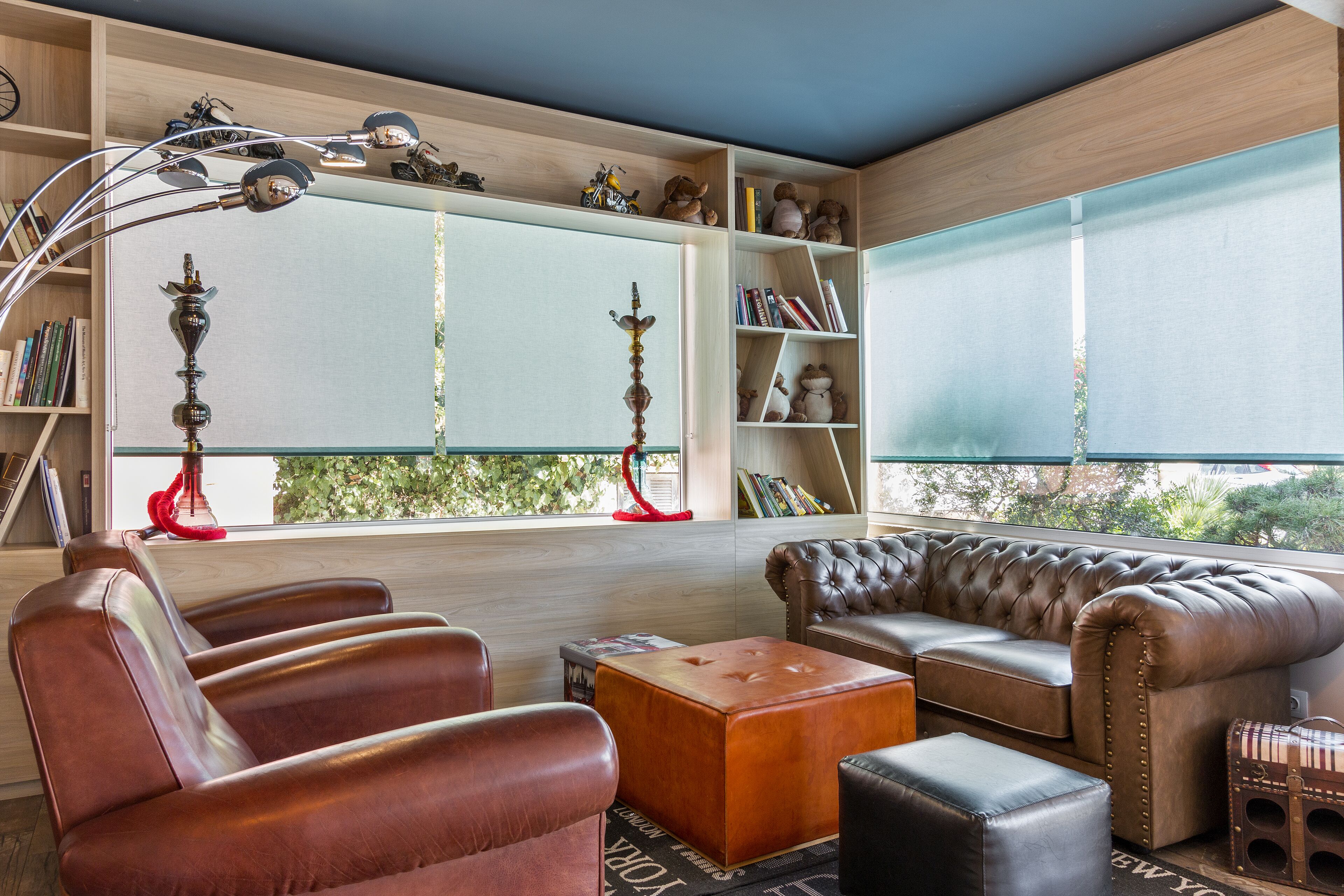 A modern living room with leather sofas, a coffee table, and a bookshelf filled with books and decorative items.
