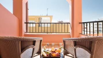 A balcony with wicker chairs and a fruit basket.