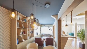 A modern living room with a wooden bookshelf, leather chairs, a glass coffee table, and pendant lighting. - Nura Santa Ponsa Pins (Calvia)