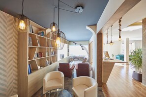 Una sala de estar moderna con una estantería de madera, sillones de cuero, una mesa de centro de vidrio e iluminación colgante.